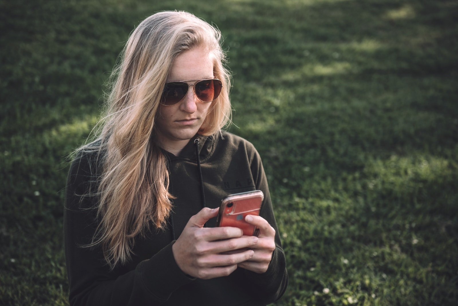 blonde woman with sunglasses using smartphone outdoor