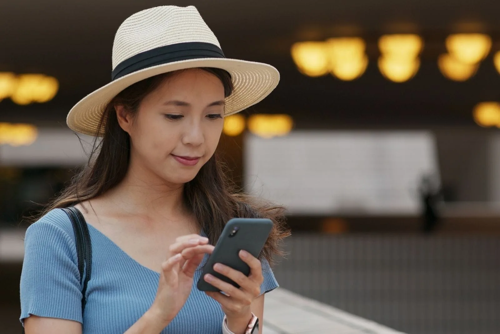 woman using smartphone with asian descent wearing hat