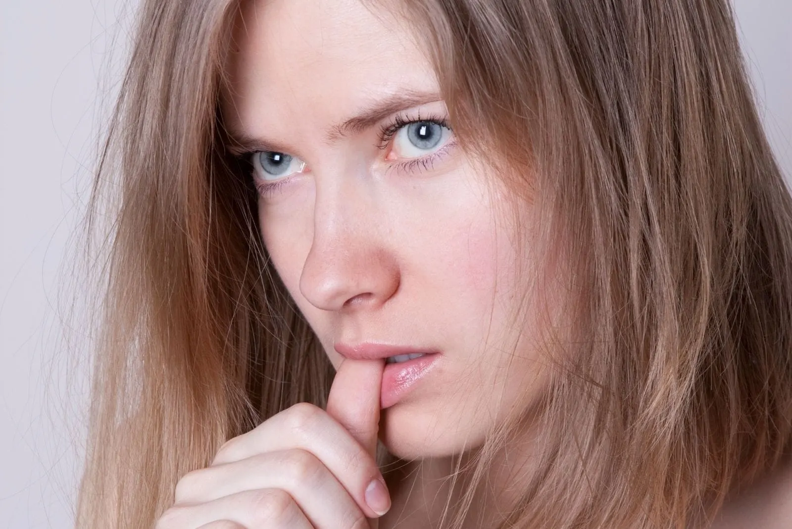 woman with a blue eye looking furiously biting her thumb