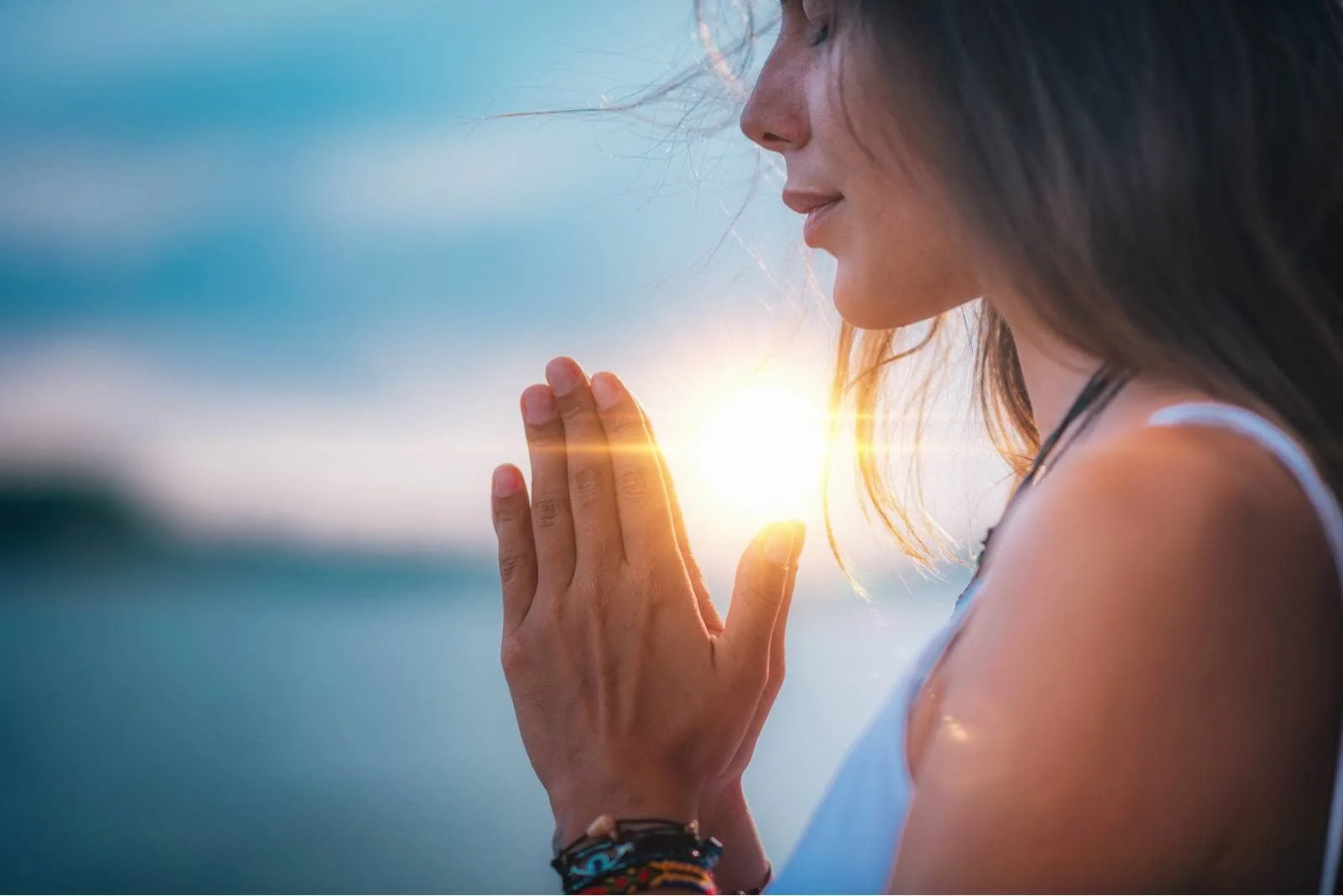 woman with praying hands meditating/praying outdoors with a sunset /sunrise 
