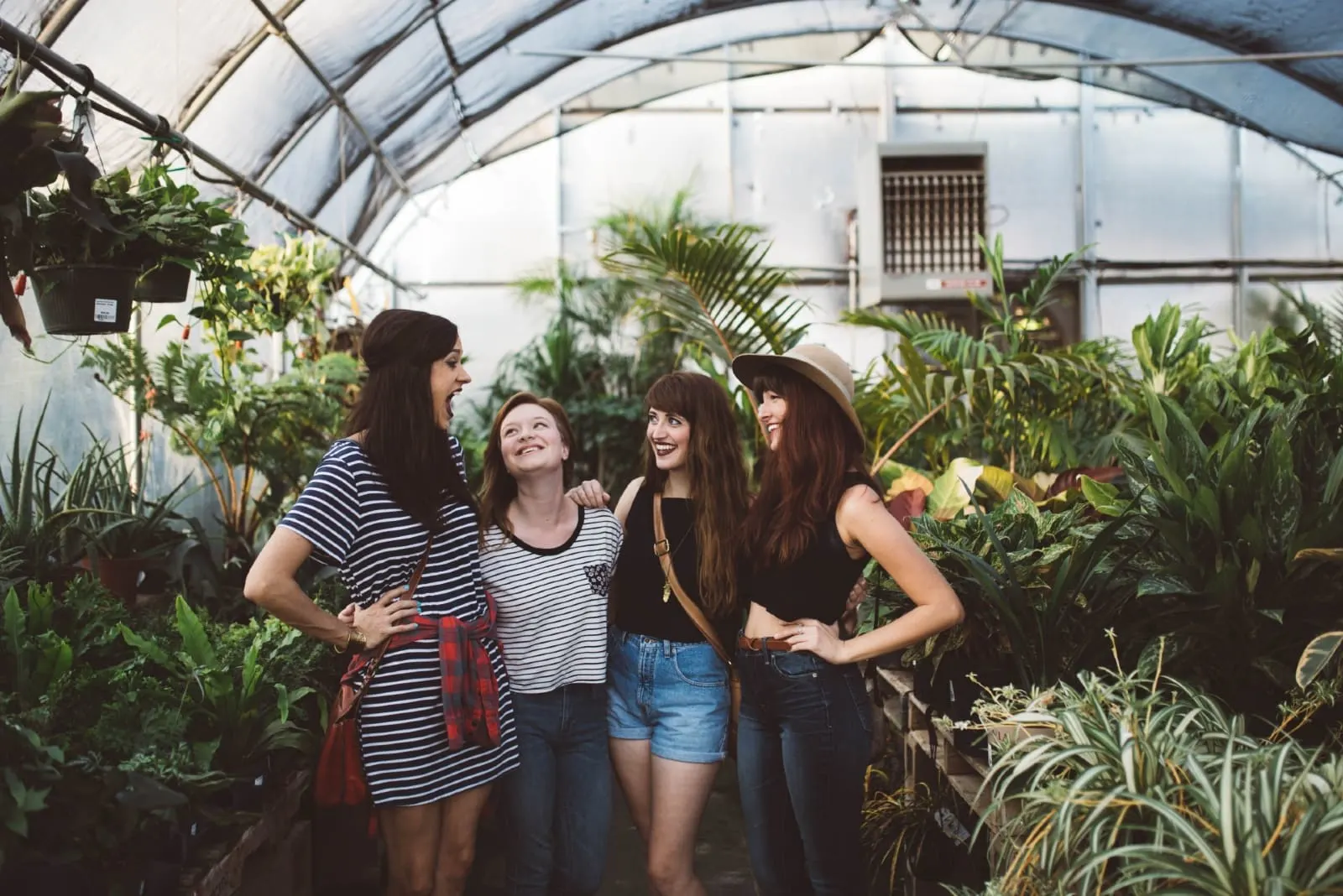four women hugging while standing near plants