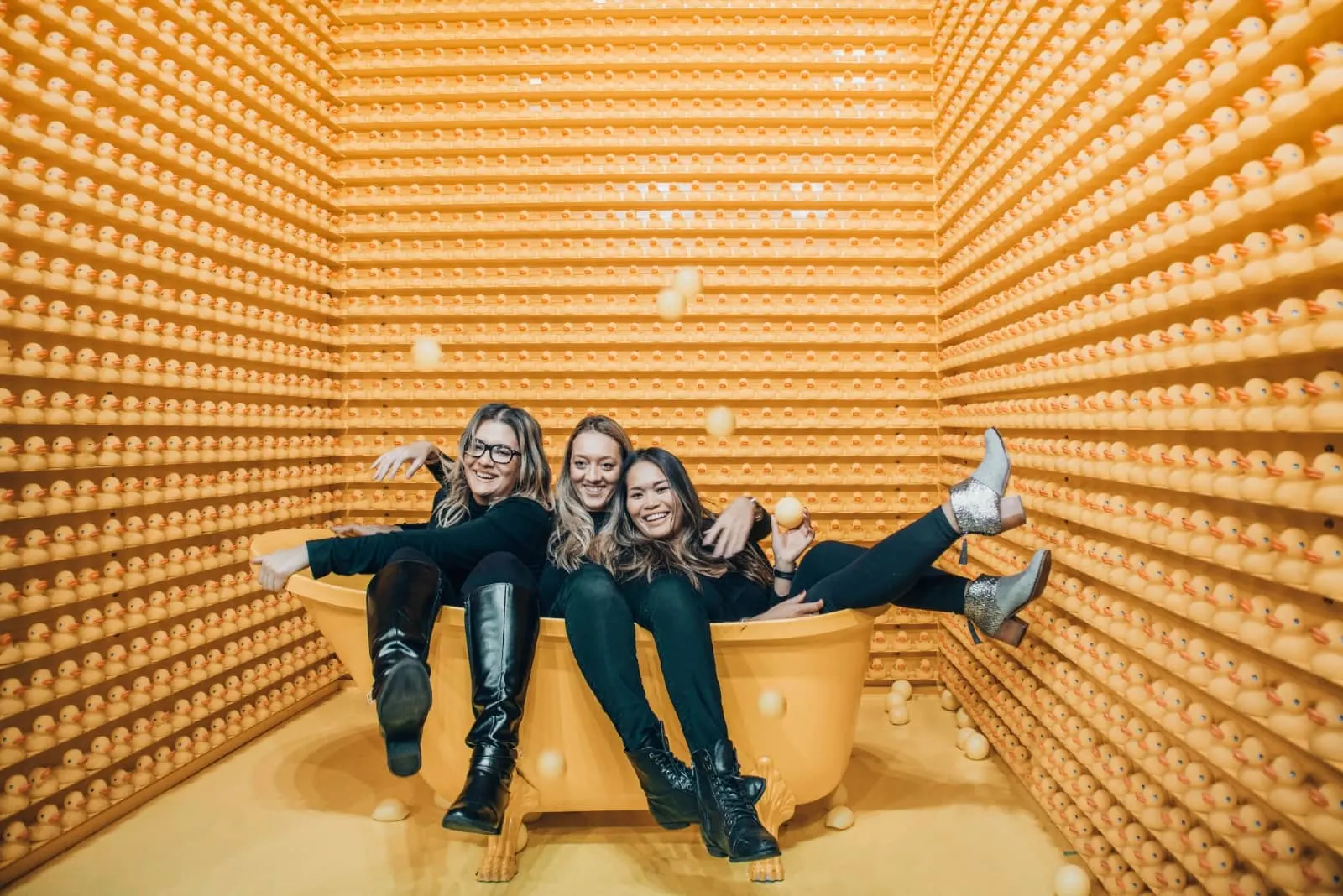 three women smiling while sitting in orange bathtub