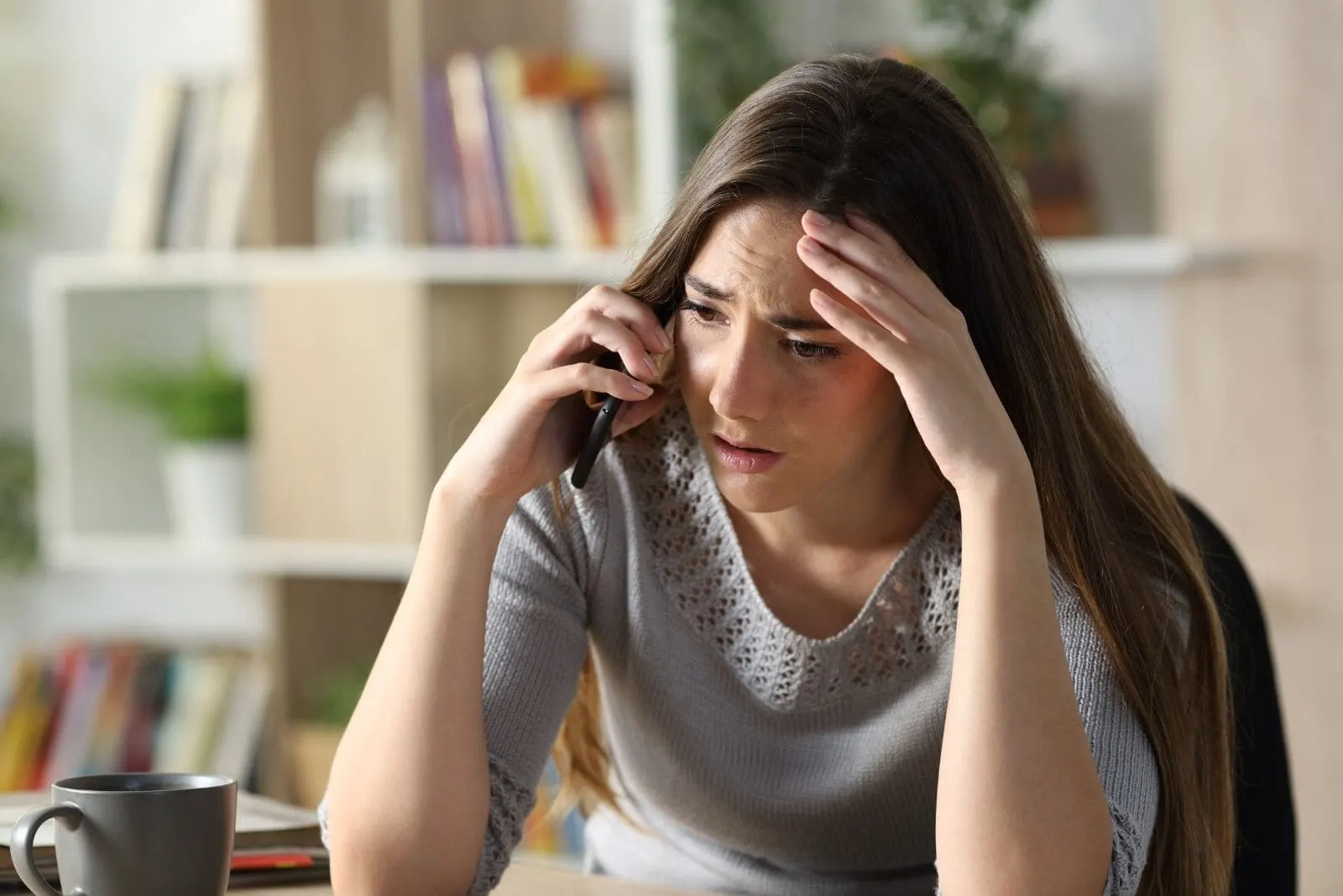 worried woman calling on the phone inside the living room