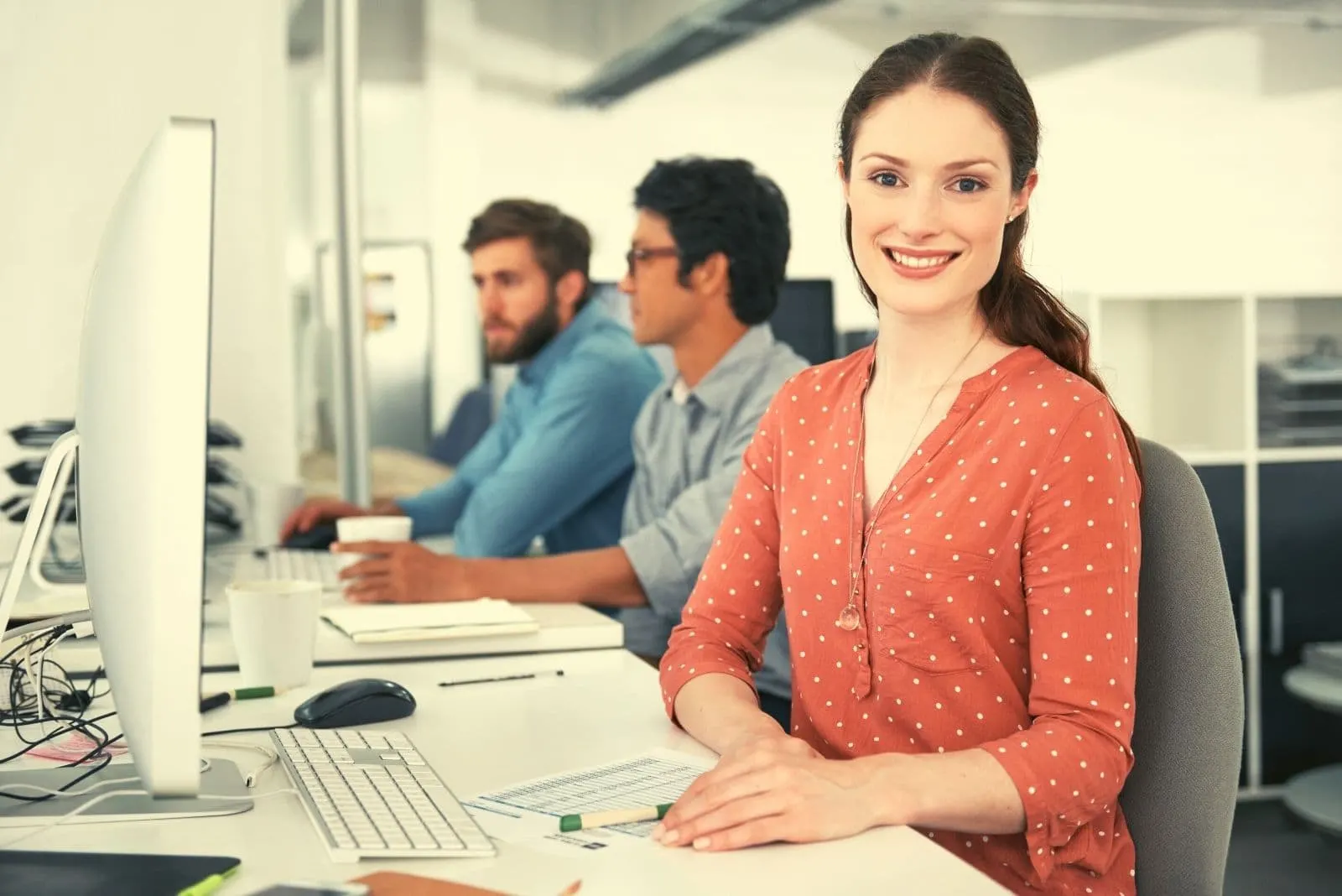 young businesswoman working in the desk with a positive mindset and other 2 two male colleague working beside her
