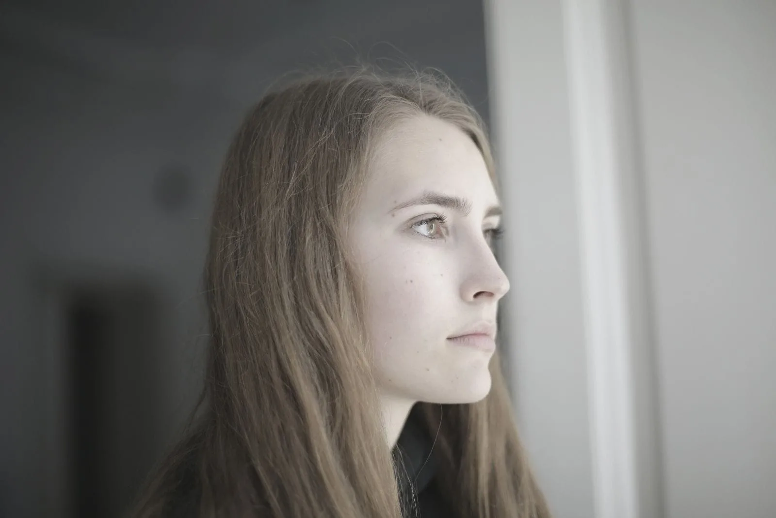 young pensive woman looking outside of the window 