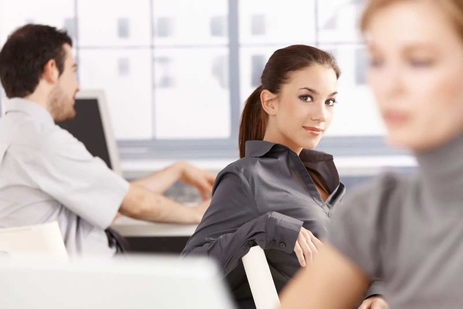 young people at office with focused on a woman smiling and looking at the camera