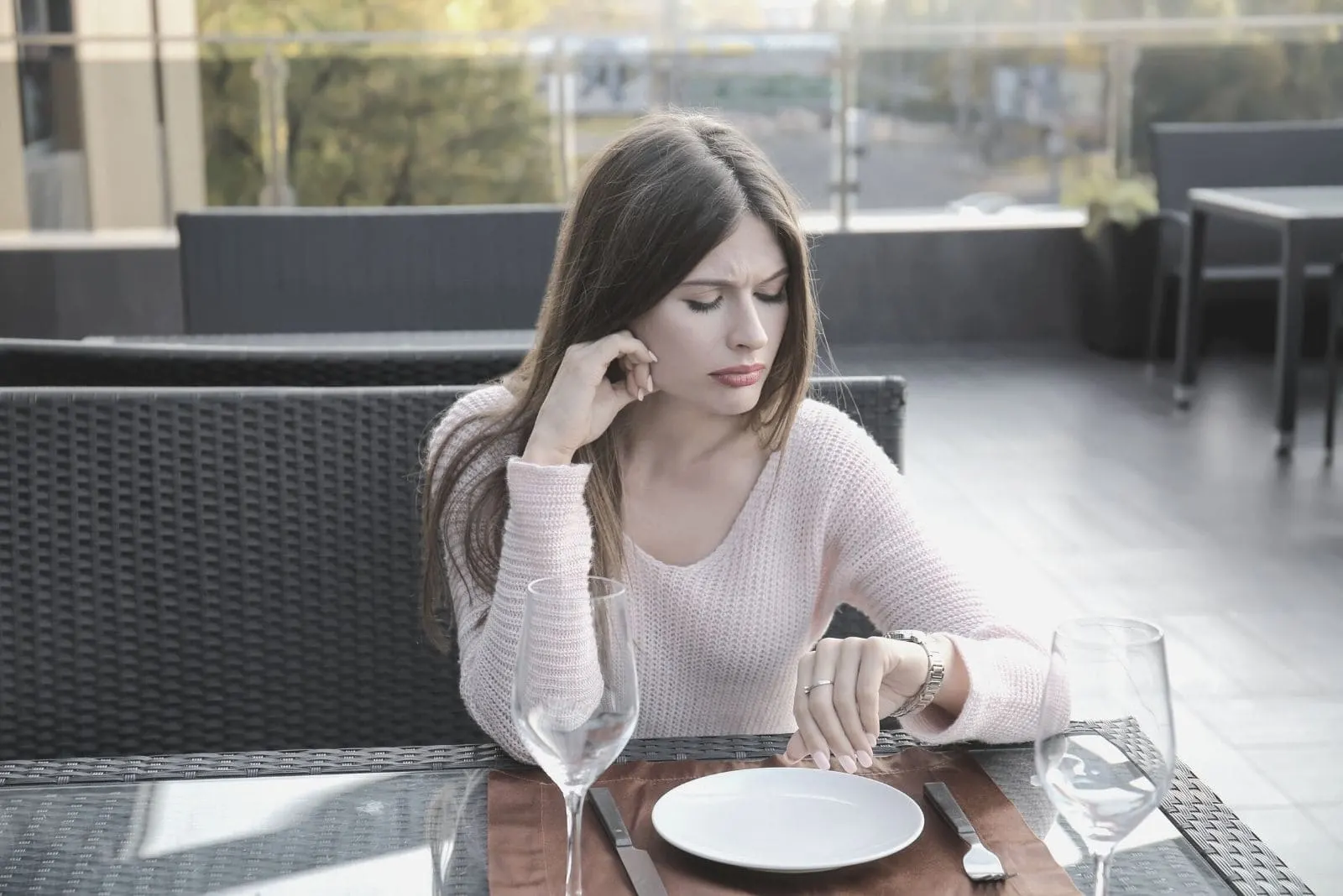 young woman looking at her watch while waiting for someone at the restaurant 