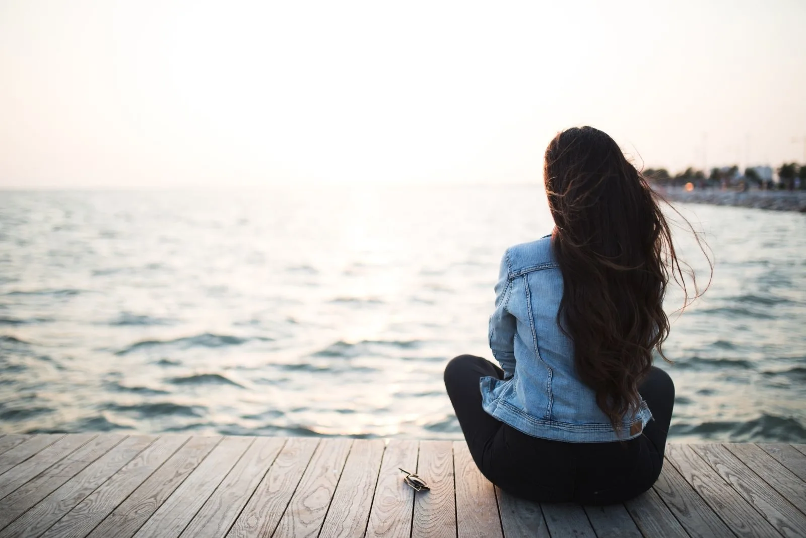young woman sitting in wooden platform looking at the sunset
