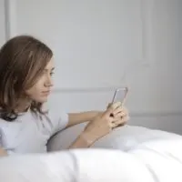 woman looking at phone while sitting on sofa
