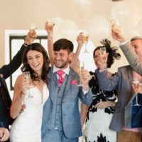 bride and groom raising their glasses with guests