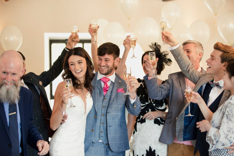 bride and groom raising their glasses with guests