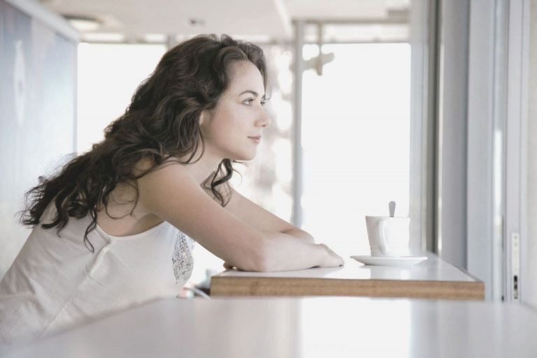 Donna pensierosa che prende il caffè al mattino in vista laterale