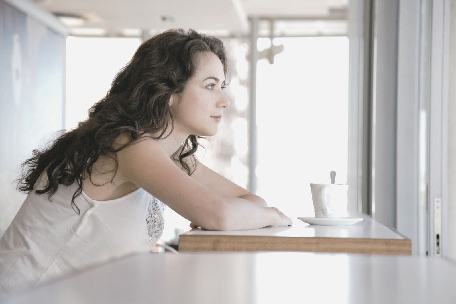 pensive woman having coffee in the morning pensively in side view