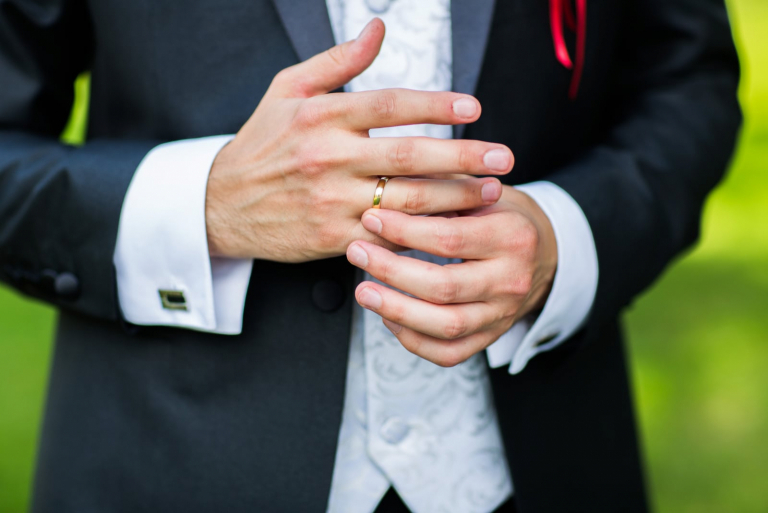 Primer plano de manos de hombre elegante con anillo, y gemelo