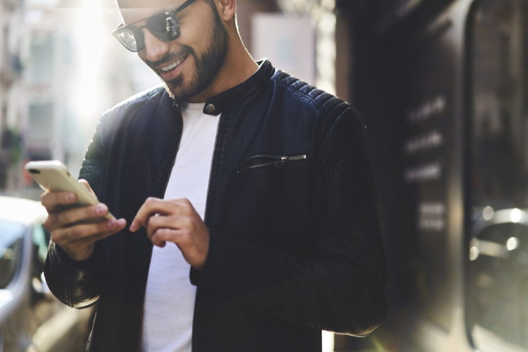 happy man in black jacket looking at phone