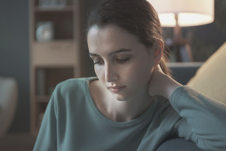 sad young woman looking down lounging in the couch
