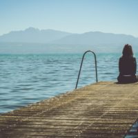 woman sitting on dock looking at water