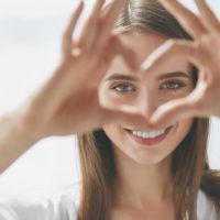 beautiful woman making a heart shaped in her hand focusing on her face