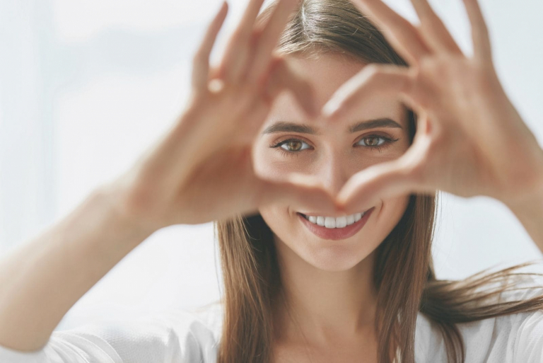 beautiful woman making a heart shaped in her hand focusing on her face