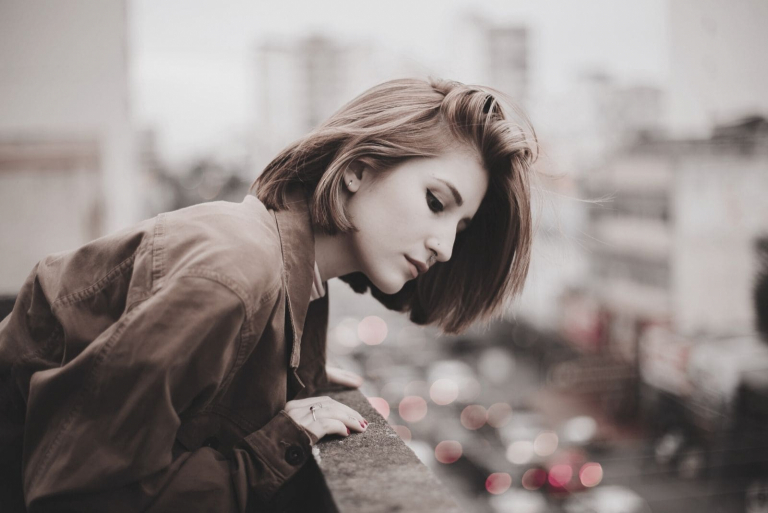 woman standing in the balcony looking in the street down below the building