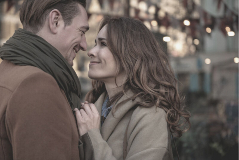 sweet couple hugging during christmas season outdoors with city lights