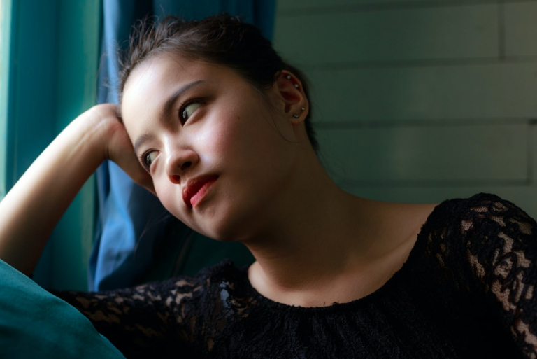 woman looking through window while sitting indoor