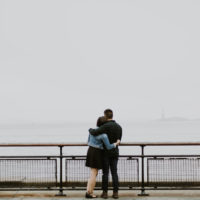 man and woman hugging while looking at water