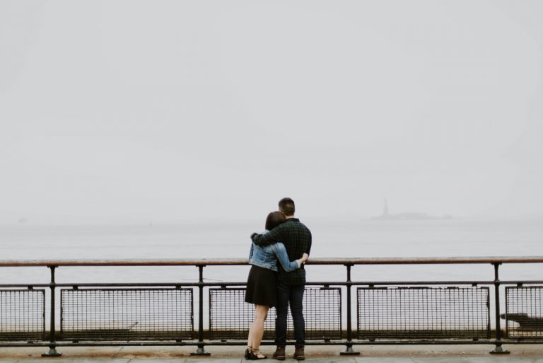 man and woman hugging while looking at water