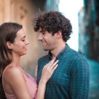 man and woman smiling while standing on the street