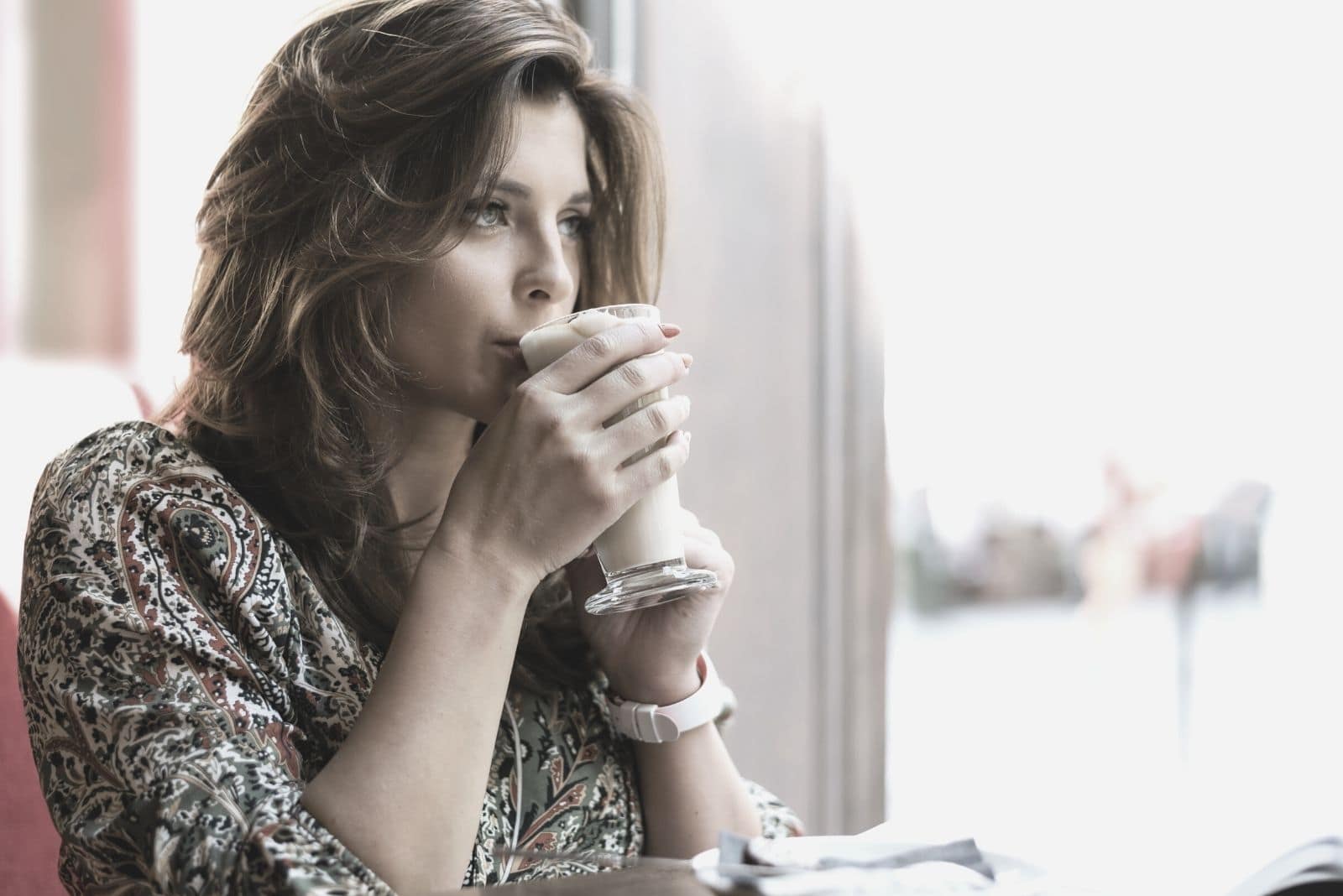 beautiful elegant woman thinking deeply inside a cafe sipping a cold latte