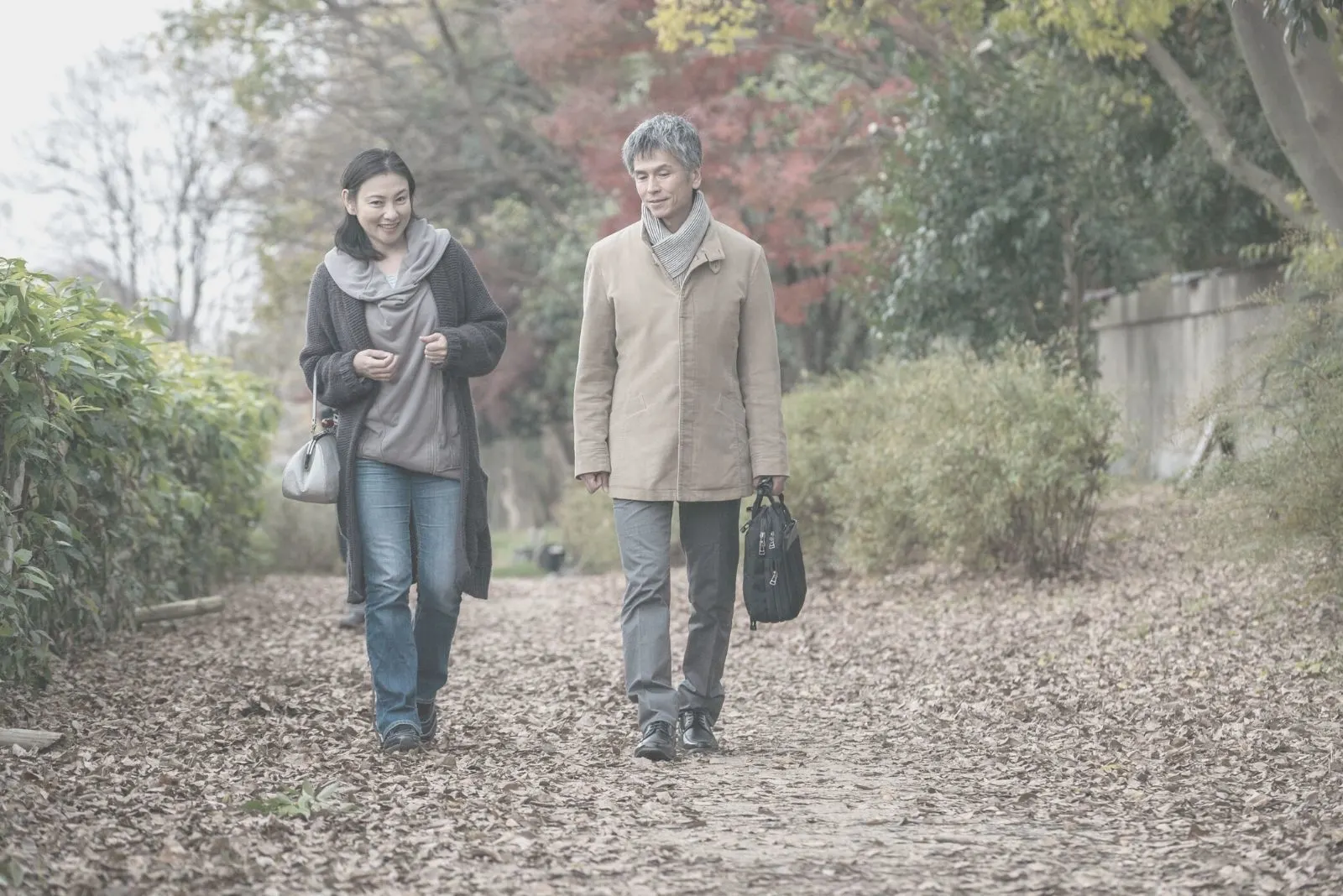 asian man and woman walking on the autumn park talking 