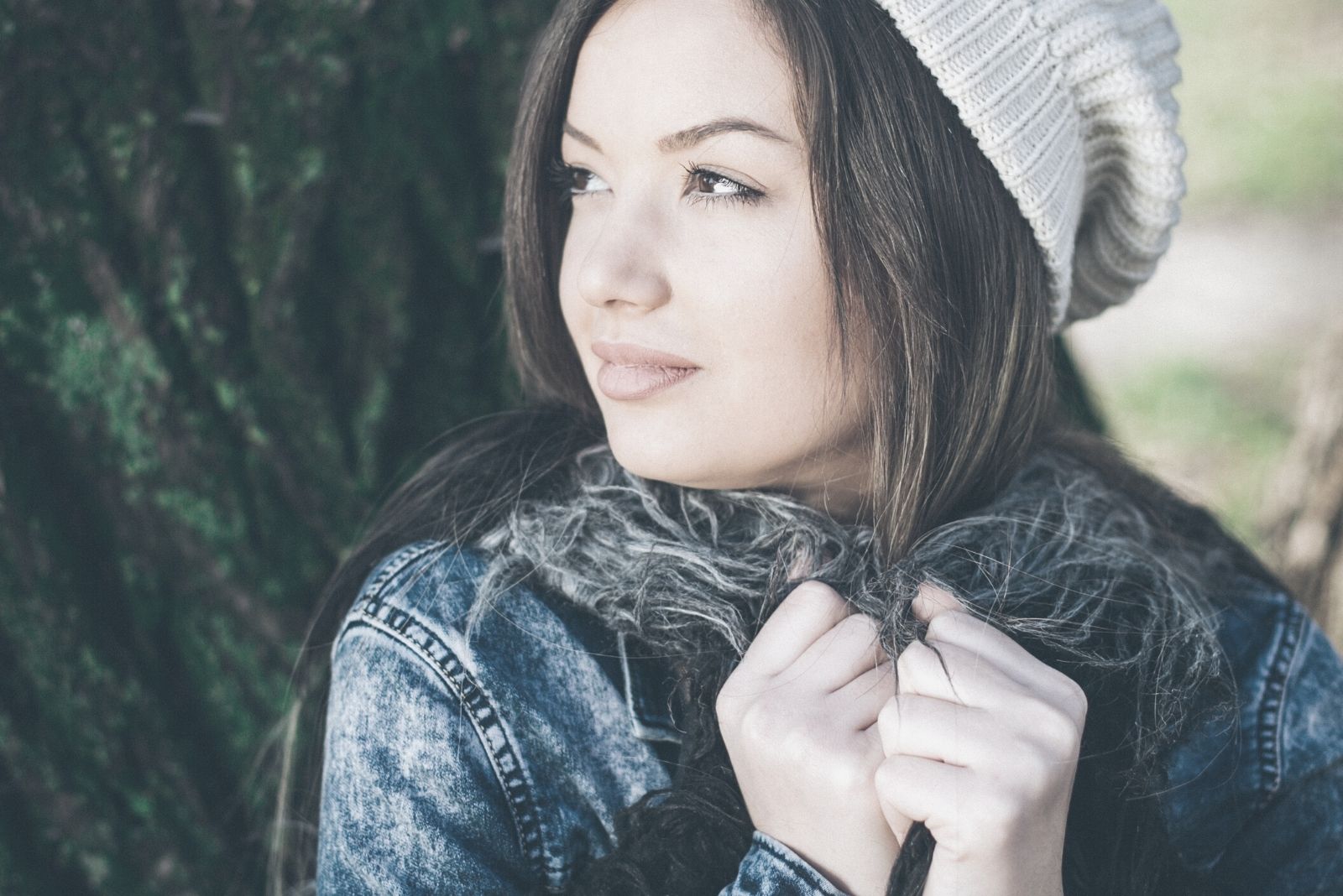 attractive young woman wearing fashionanable autumn wear standing near the tree thinking deeply