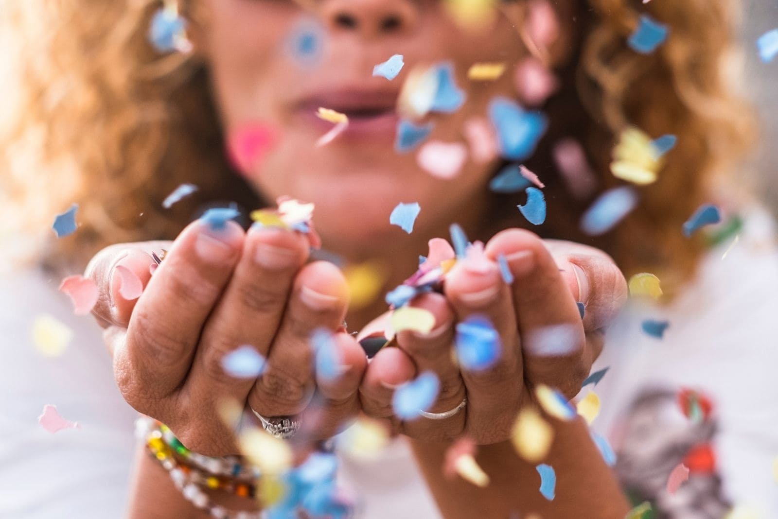 bella donna defocalizzata che soffia coriandoli sulla mano per concetto di celebrazione