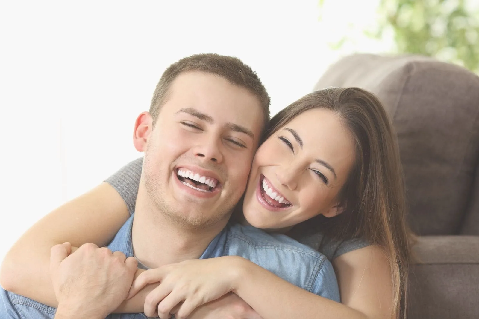 cheerful couple cuddling and hugging inside the living room 