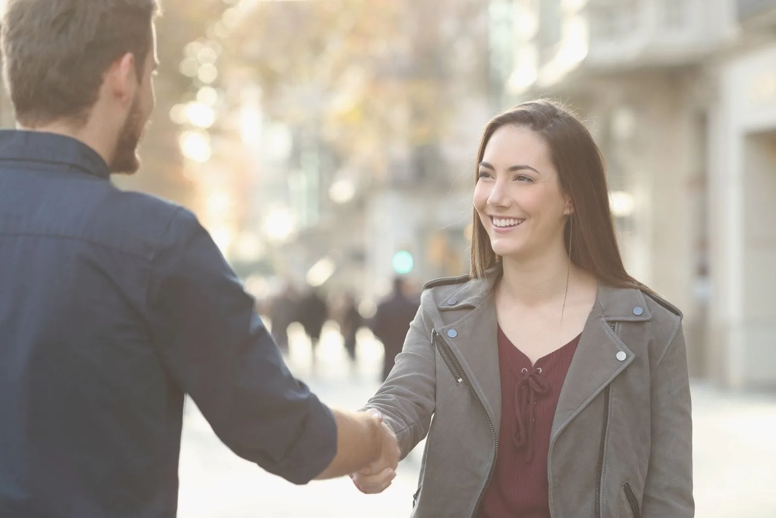 cheerful man and woman handshaking in a city street