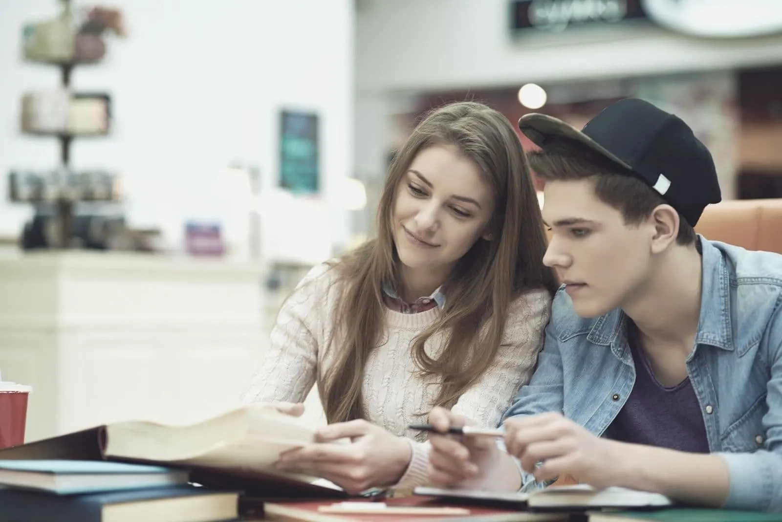 college couple studying inside the cafe with books on the table 