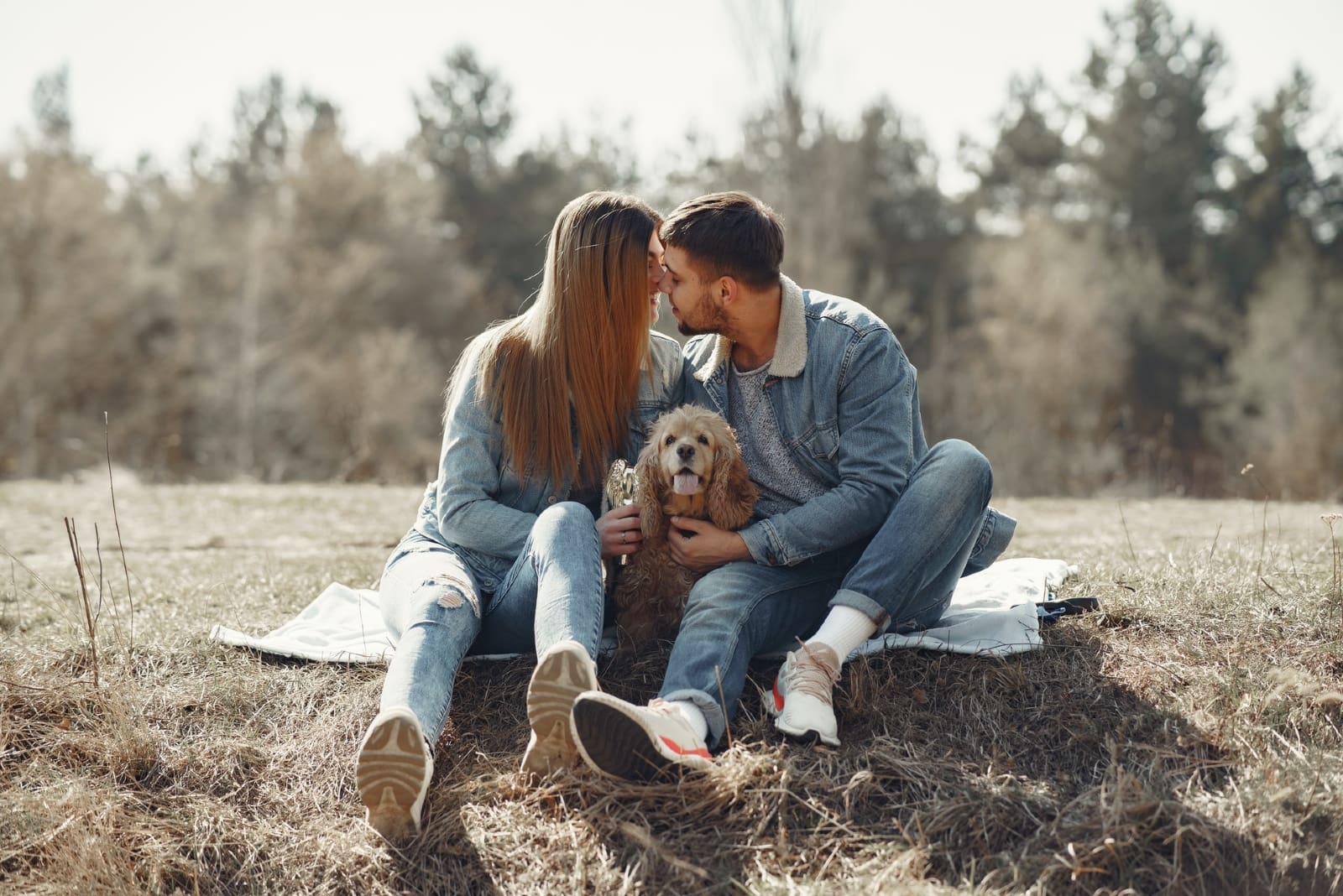 man and woman about to kiss while sitting near dog