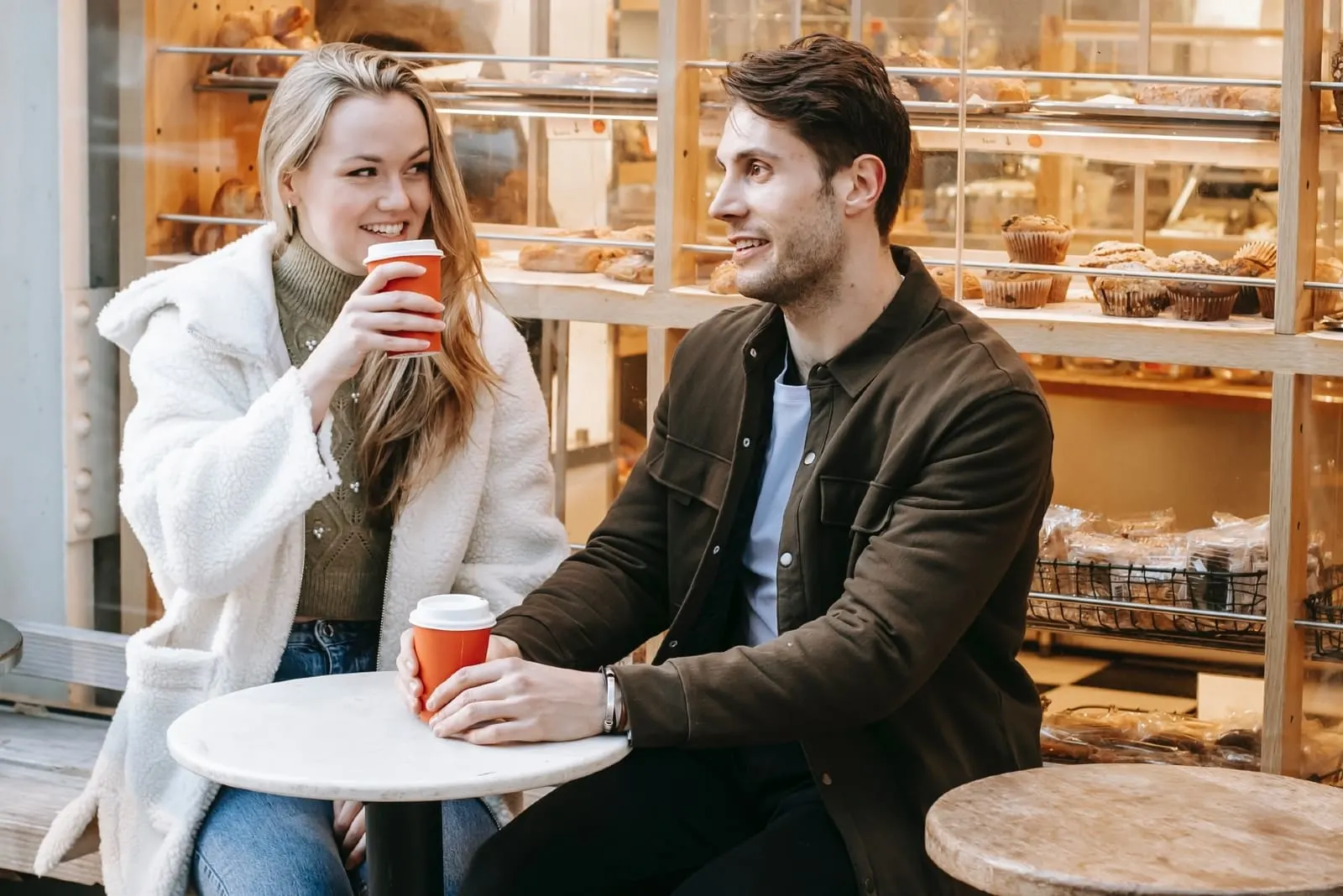 man and woman having coffee while sitting outdoor