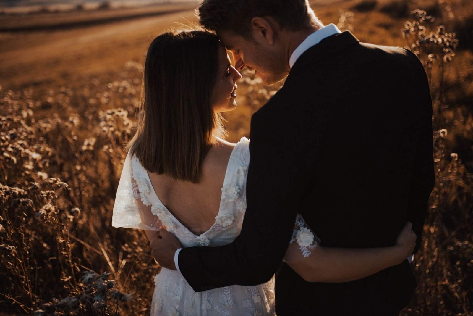 bride and groom hugging while standing in the field