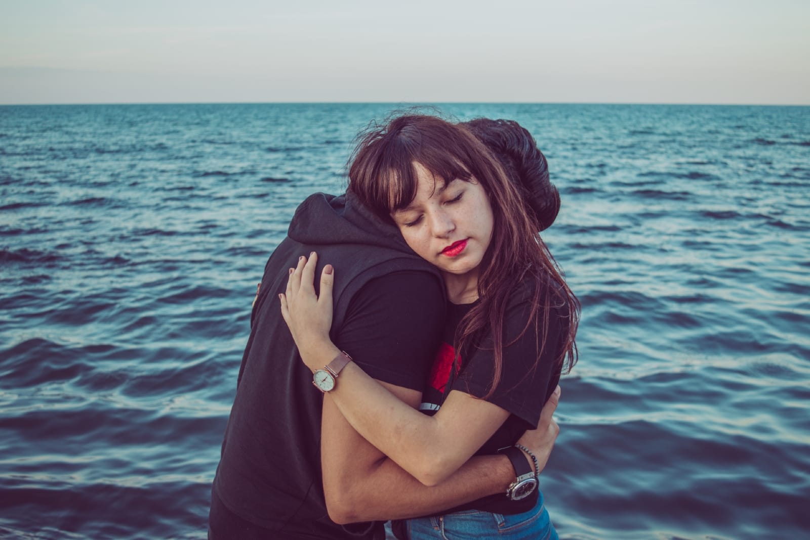 man and woman hugging while standing near sea