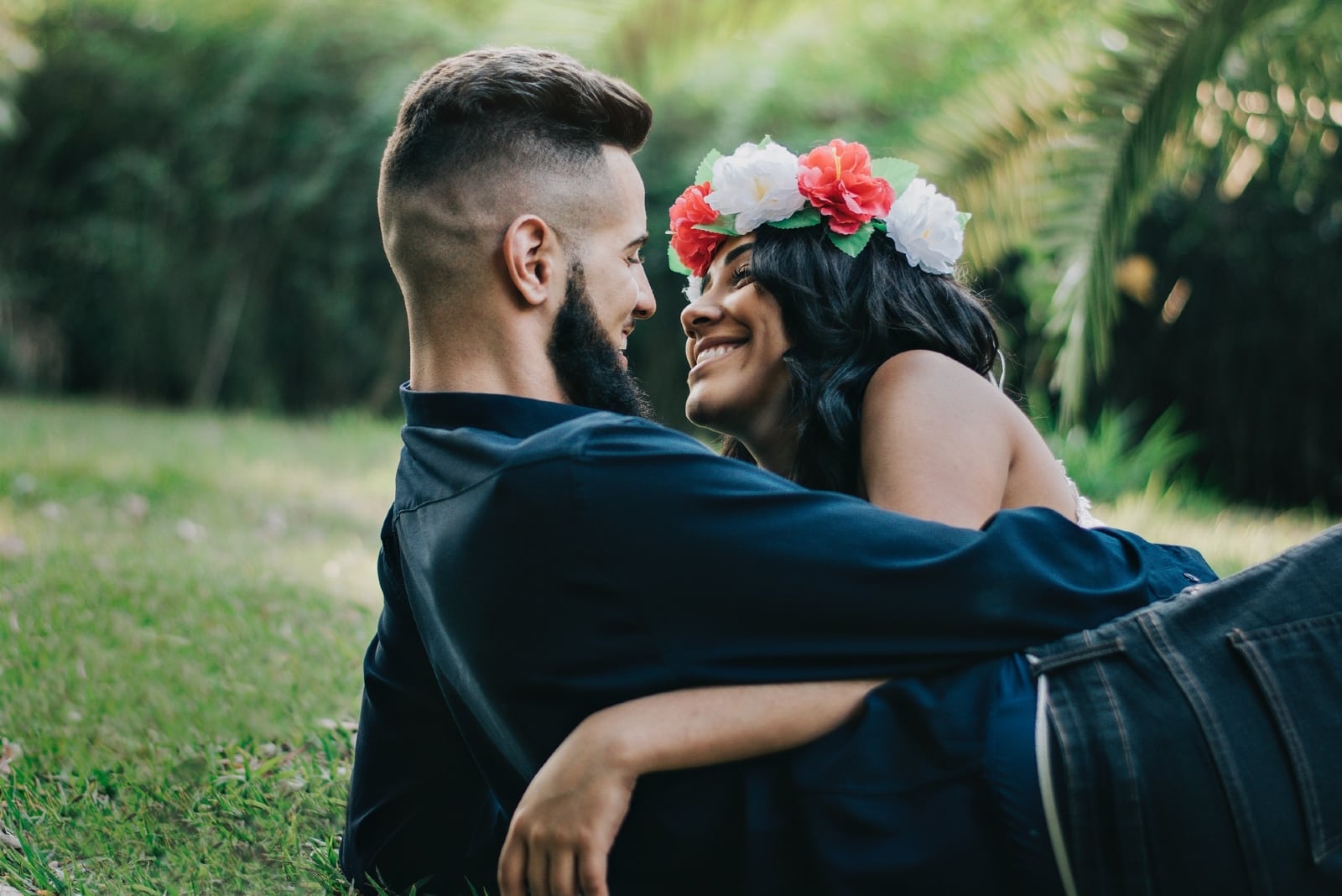 man and woman hugging while laying on grass