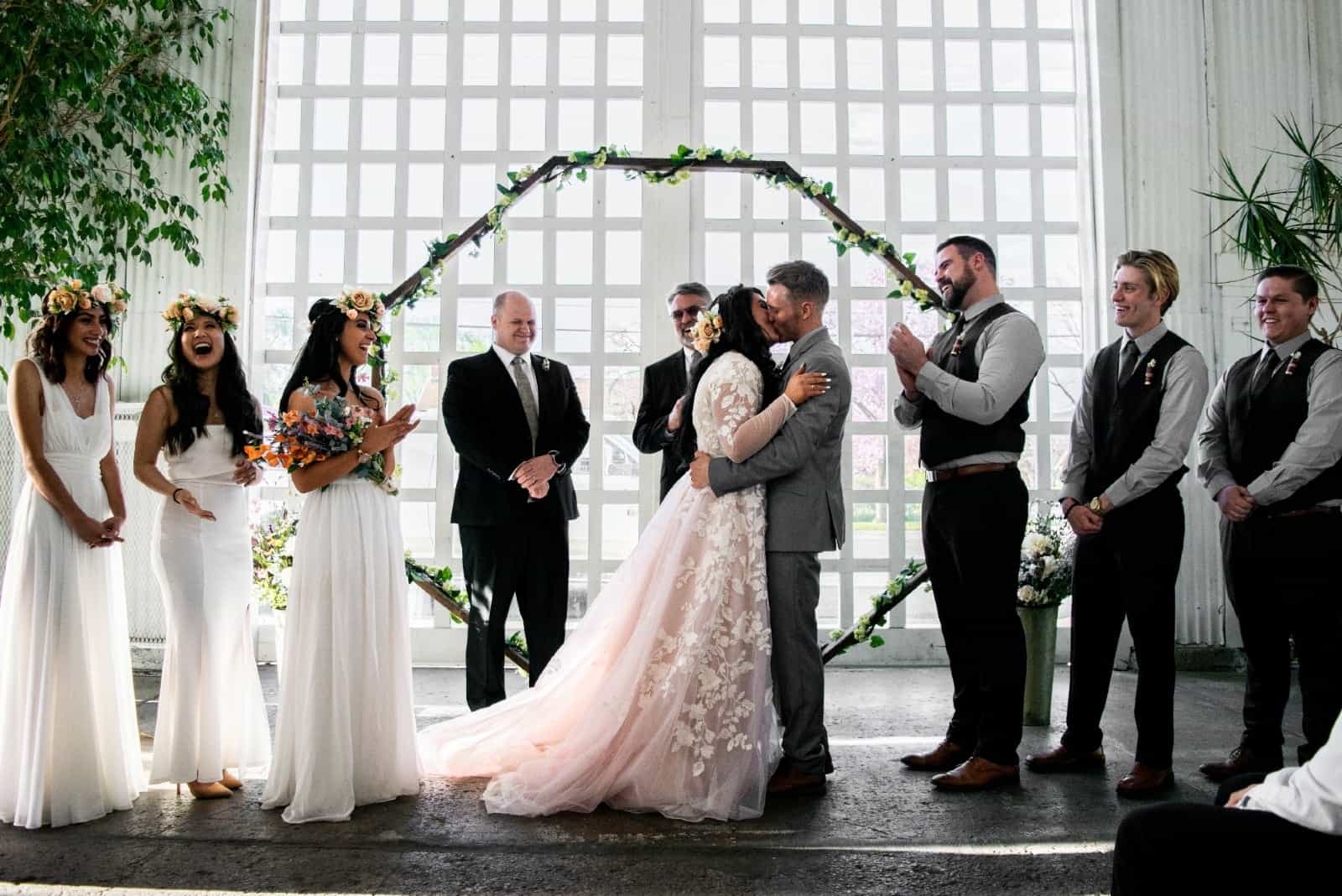 novios besándose cerca de las damas de honor