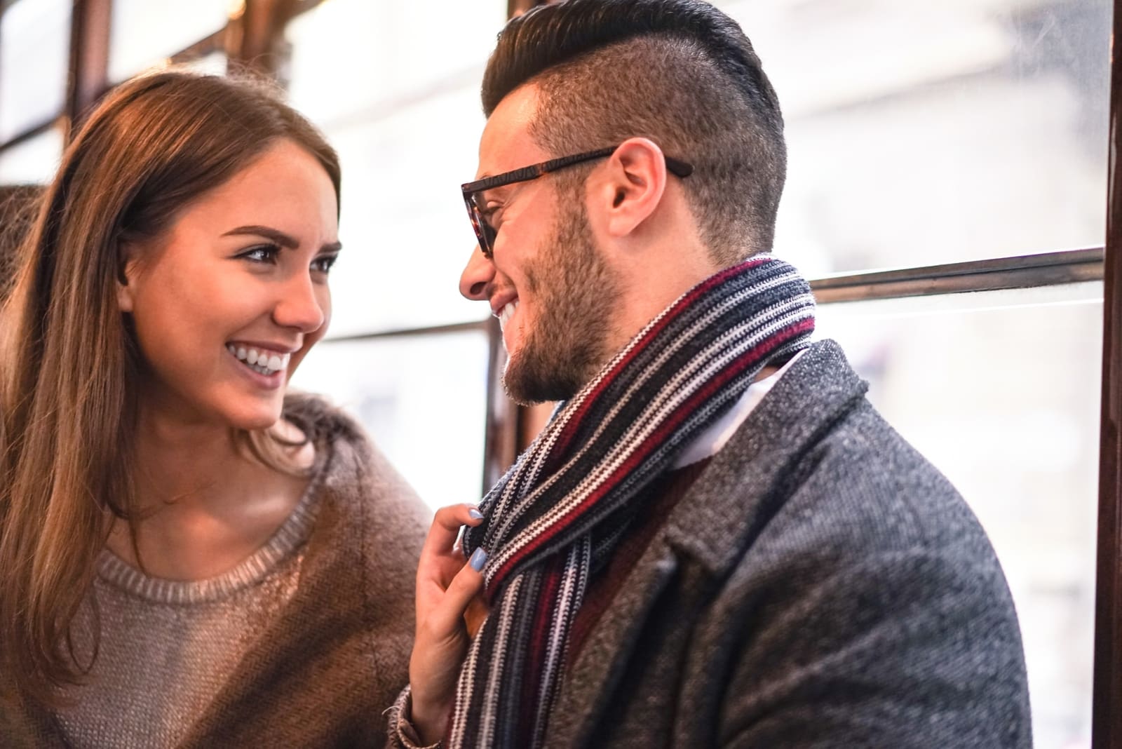 man and woman laughing while standing near window