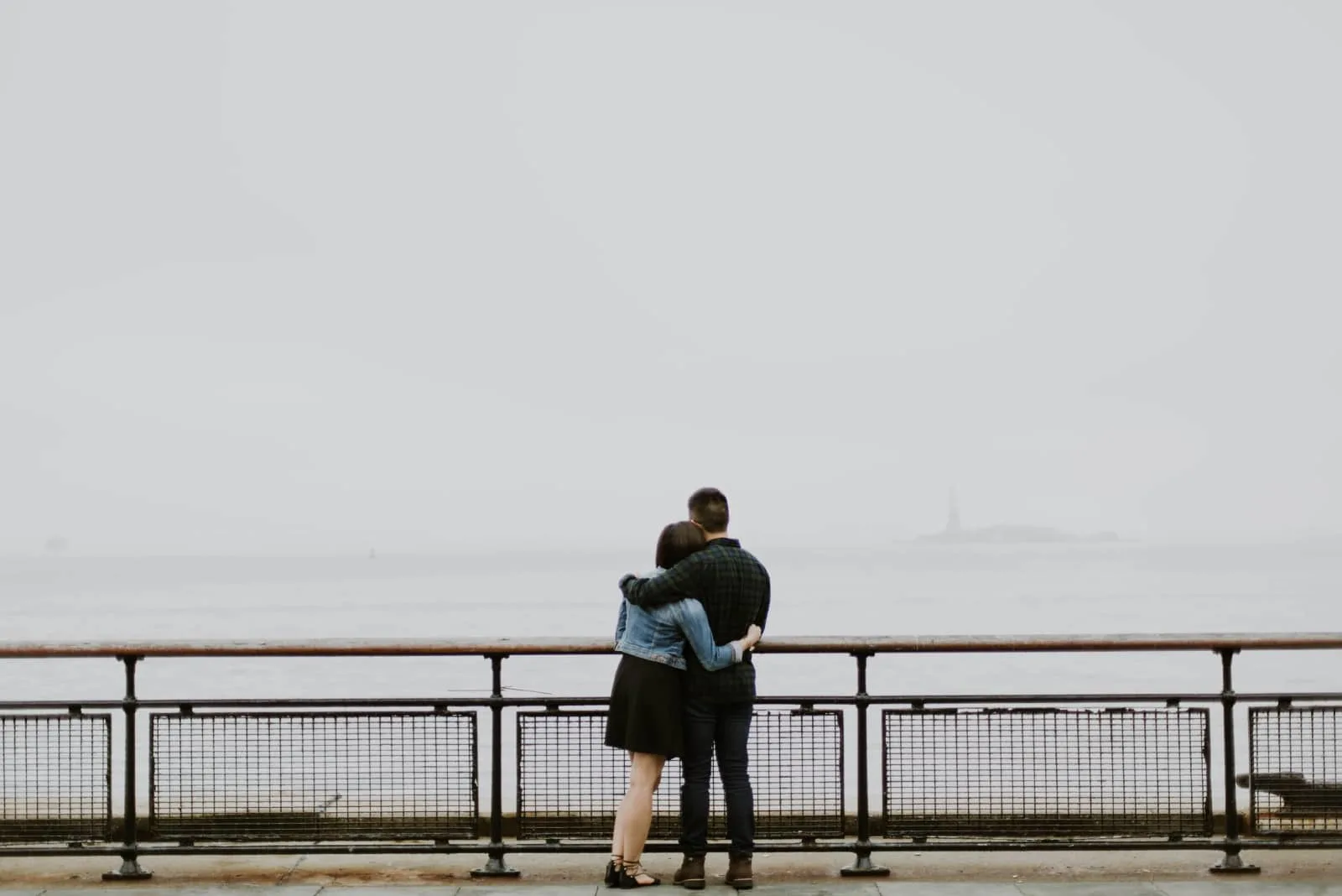 man and woman hugging while looking at sea