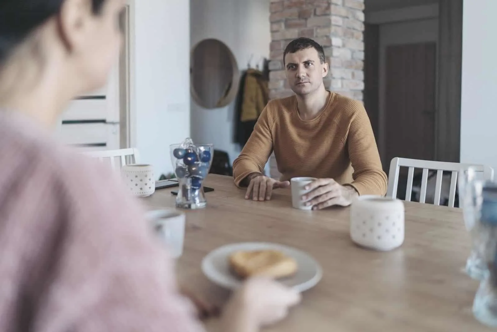 couple sitting in the kitchen having serious conversation during breakfast