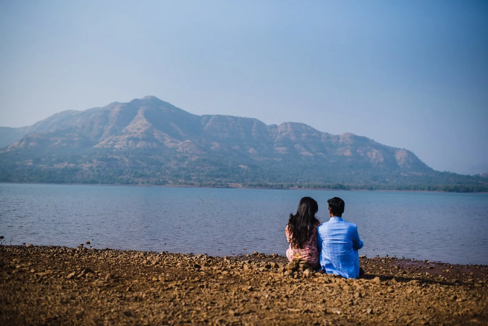 man in blue shirt and woman sitting near water