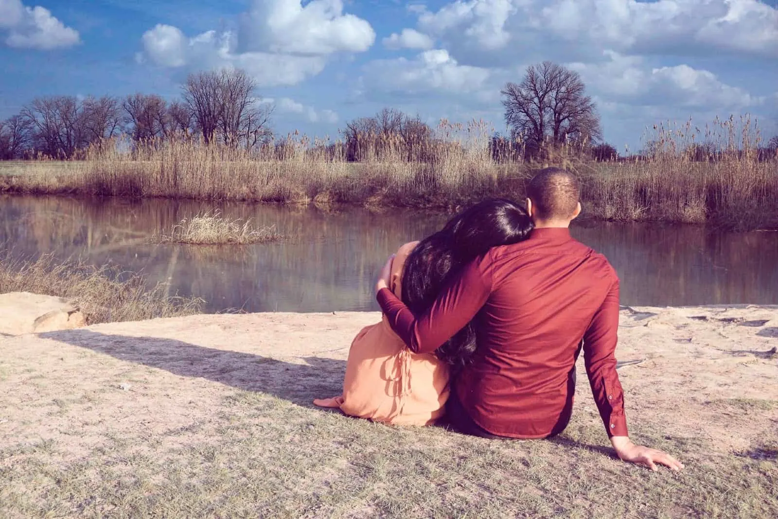 man and woman hugging while sitting near water