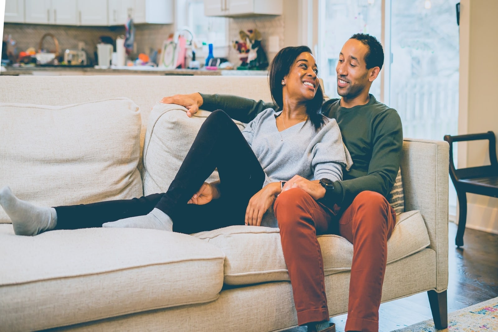 man and woman smiling while sitting on sofa