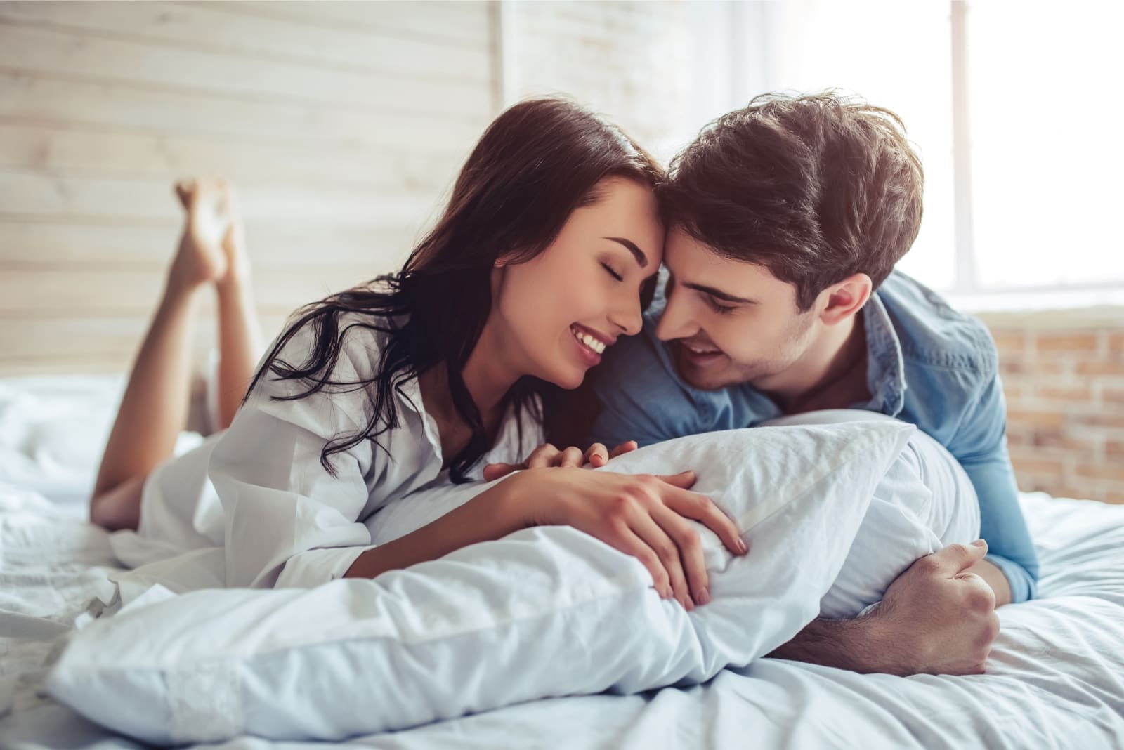 man and woman smiling while laying on bed