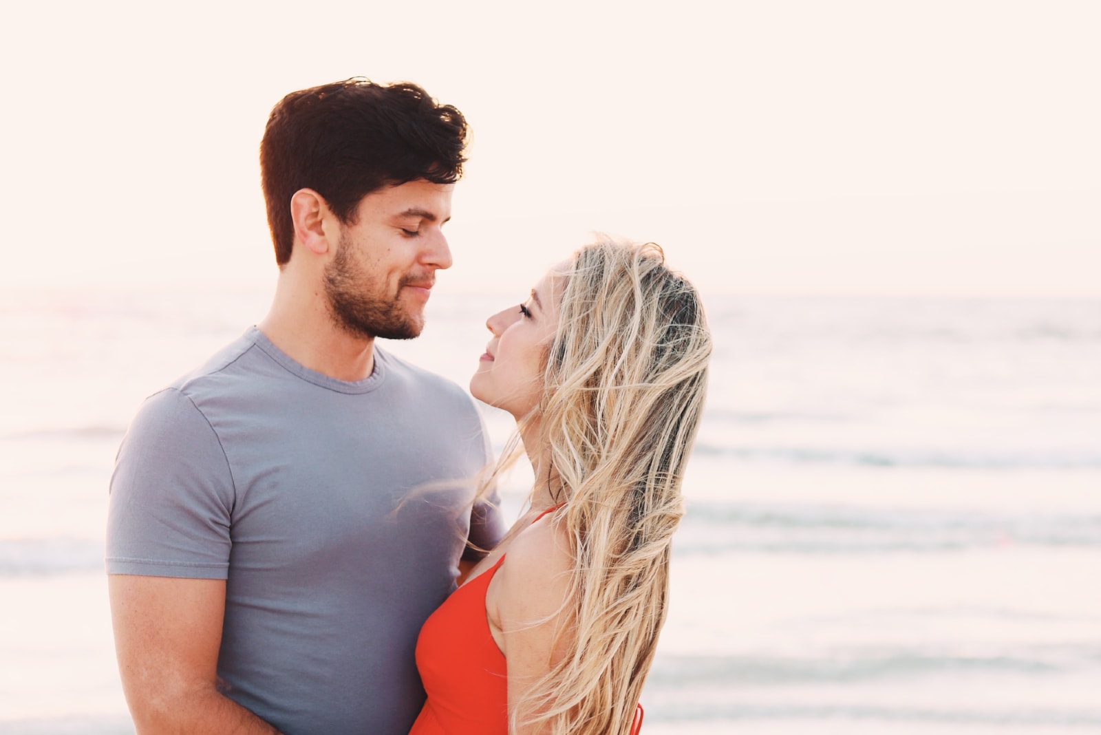 man and woman making eye contact while standing near sea